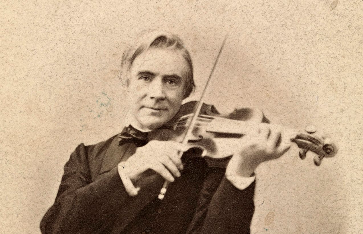 Fotografi av Ole Bull i halvfigur som spiller fiolin og ser i kamera mens han smiler.