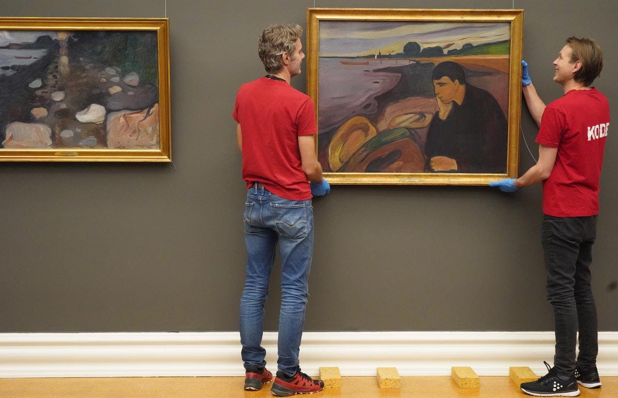 Two men mounting a painting by Edvard Munch