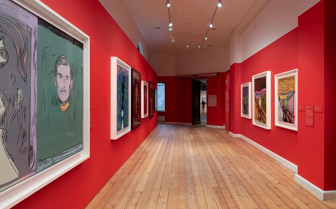 En rekke malerier av Andy Warhol i utstillingen brikker, i et rom med røde vegger