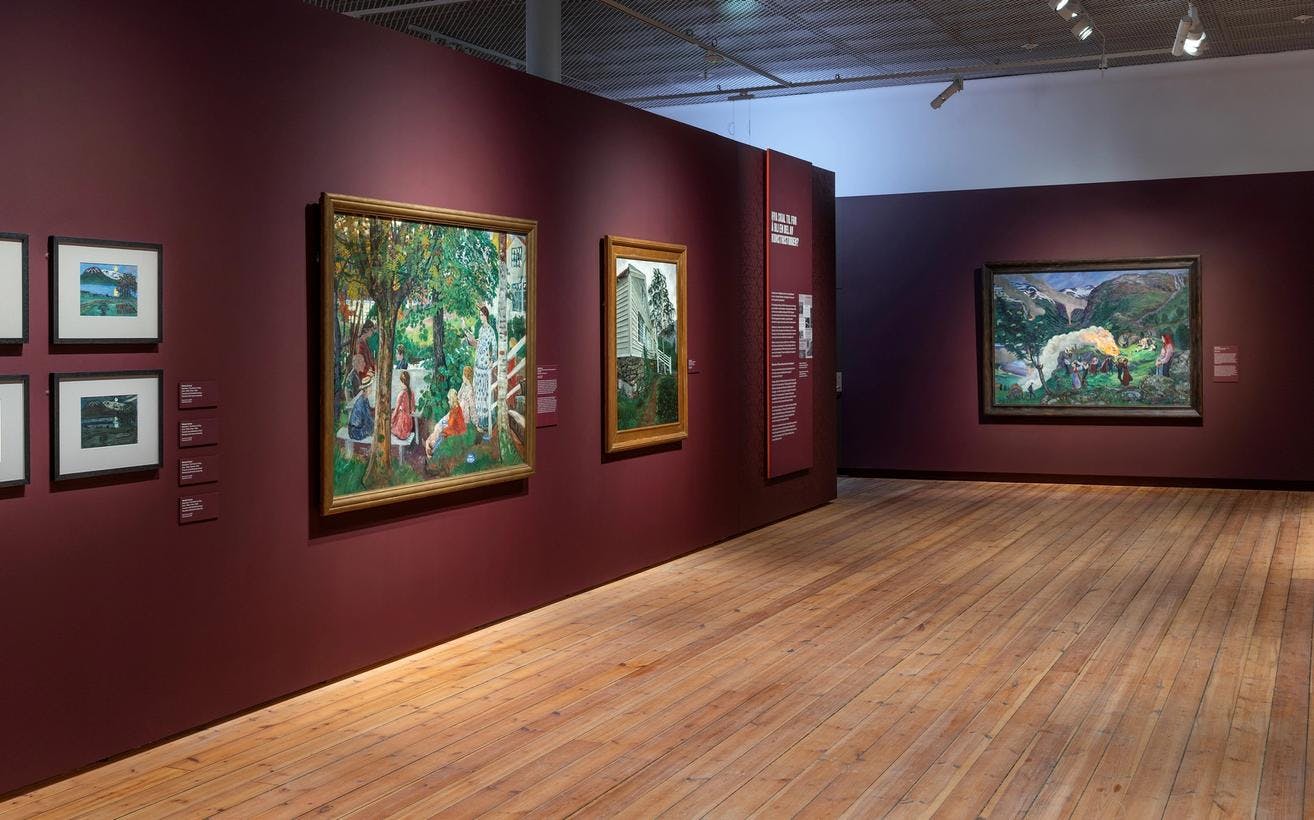 En rekke malerier av Nikolai Astrup i utstillingen Brikker, i et rom med mørk røde vegger