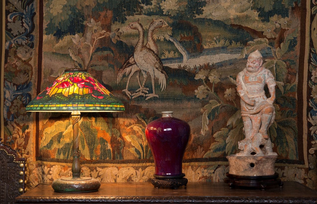 Fra en tidligere presentasjon av Singersamlingen, hvor vi ser en lampe, en vase og en kinesisk figur plassert oppå en flate, foran en tekstil som henger på veggen.