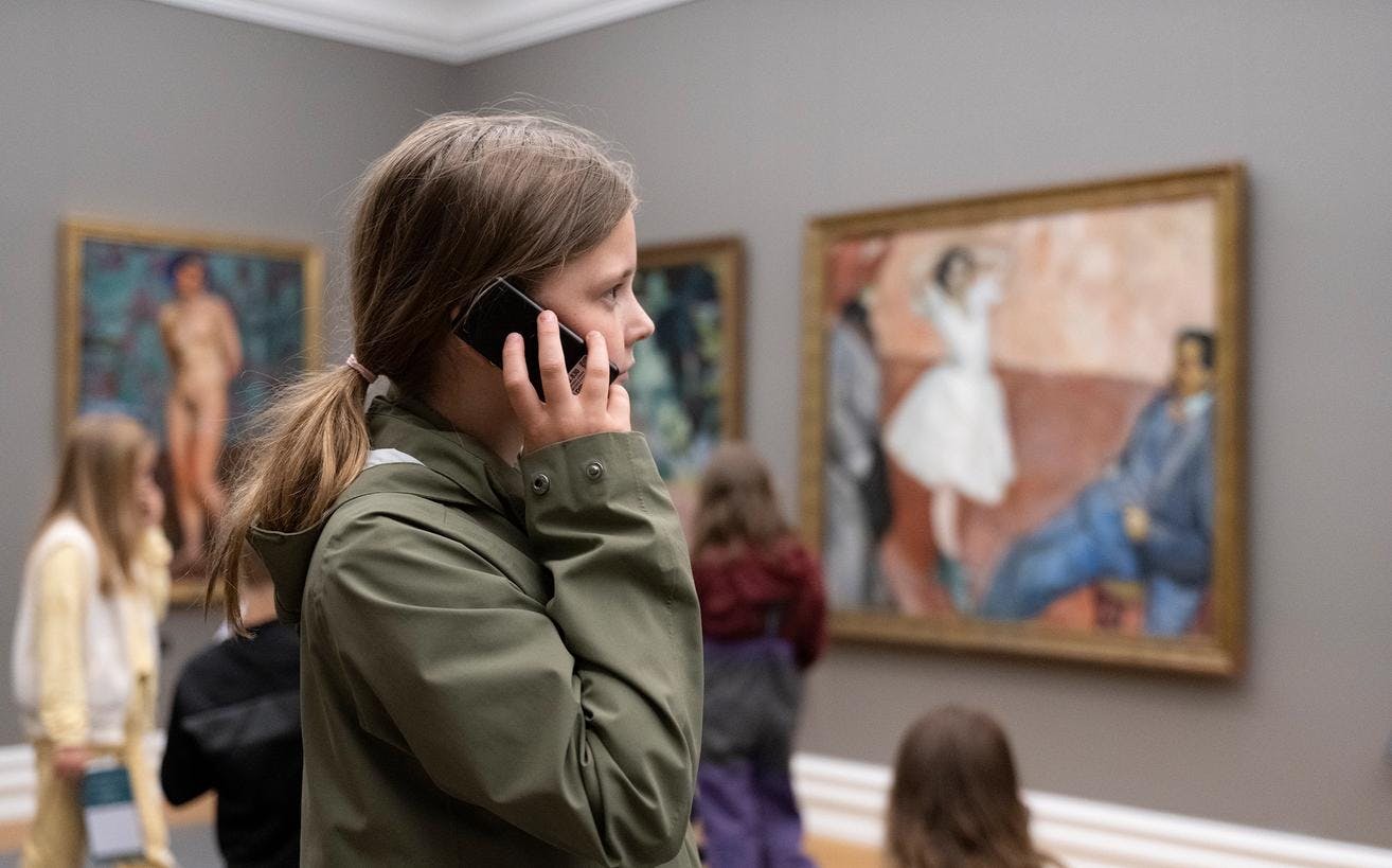 A young girl listening to an audioguide in the Rasmus Meyer museum.