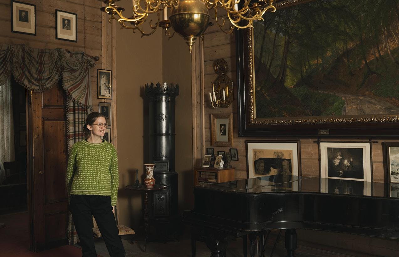 En omviser inne i Griegs villa, i stuen ved flygelet.