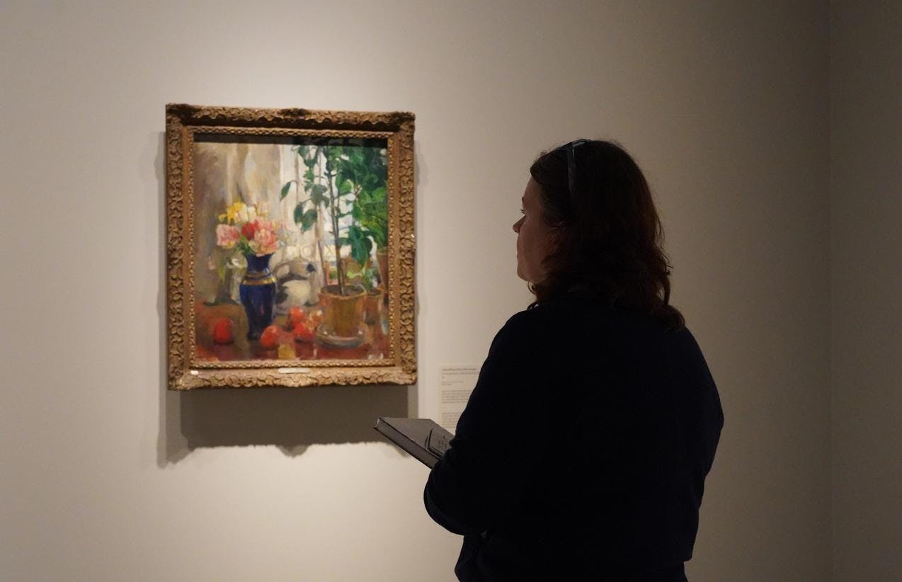 En person foran et maleri av Harriet Backer
