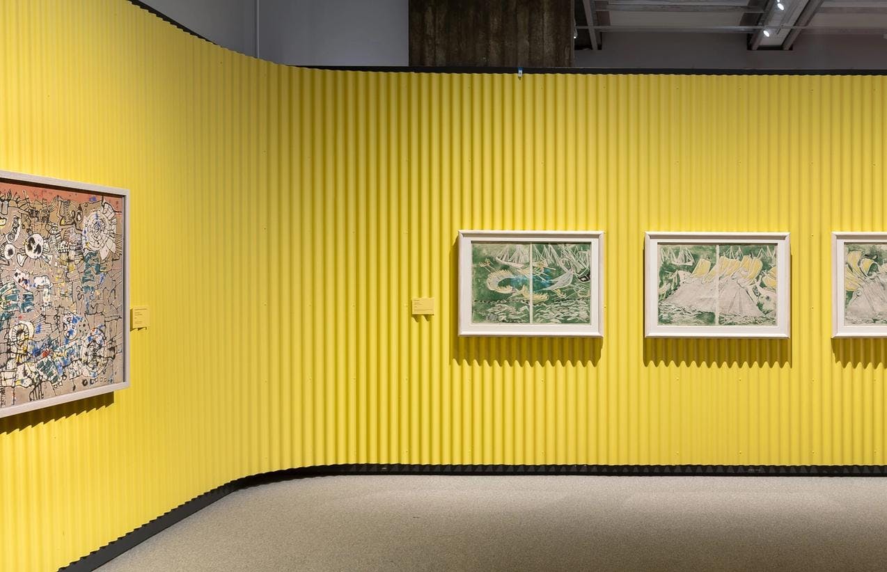 En gul utstillingsvegg, hvor det henger fire malerier