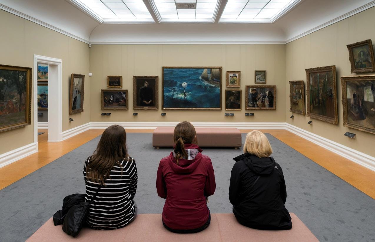 Tre barn sitter på en benk i museet Rasmus Meyer, med ryggen til, mens de betrakter malerier