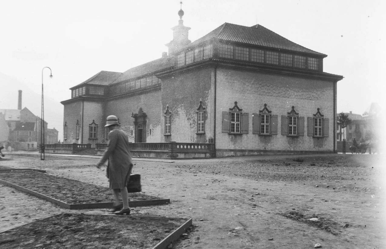 Sort-hvitt fotografi som viser en kvinne som går foran museet Rasmus Meyer